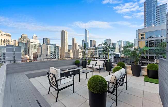 A rooftop patio with chairs and tables overlooking a city skyline.
