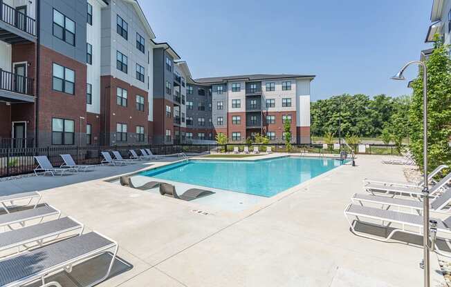 Hermitage Apartments - Expansive Pool And Pool Deck, Lounge Chairs, And Maintained Landscaping. Apartments Are In The Background.