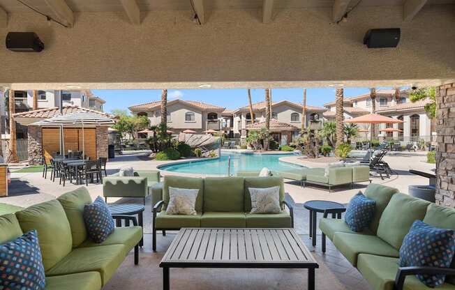A patio with a pool and green couches.