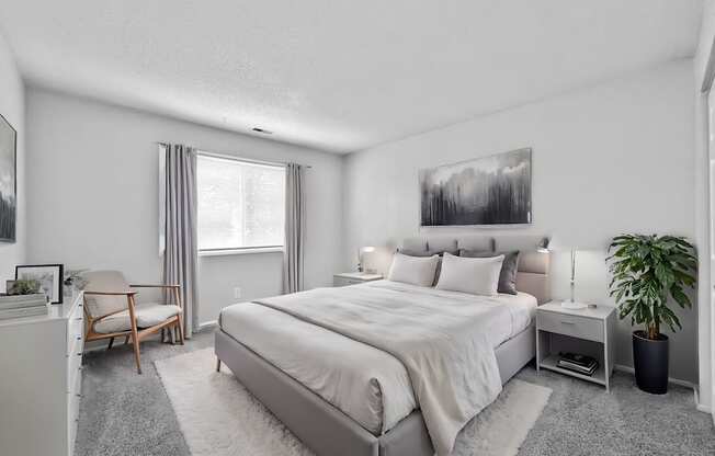 A bedroom with a large bed, a chair, a potted plant, and a painting on the wall.