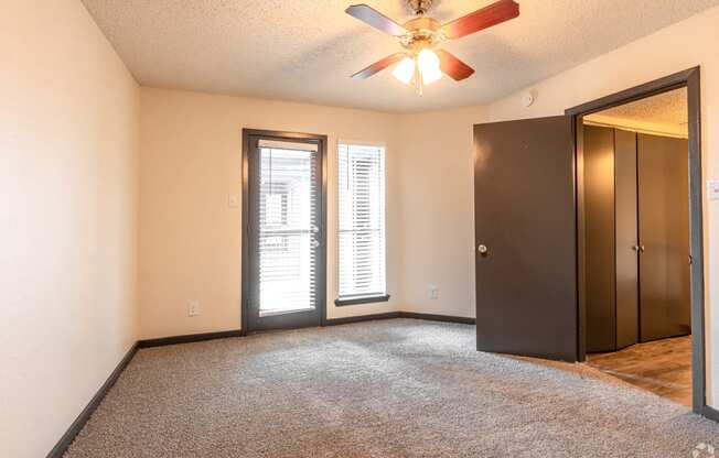 an empty living room with a ceiling fan and a door to a closet