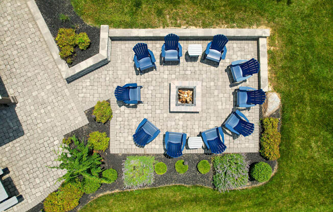 A fire pit surrounded by blue chairs in a garden.