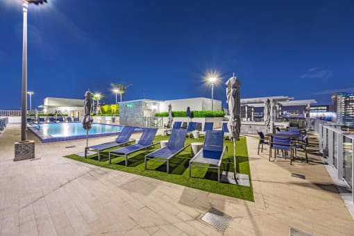 a pool with lounge chairs and a poolside bar at night