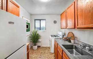 A small kitchen with a white fridge and a window.
