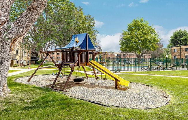A playground with a blue and yellow slide and a yellow slide.