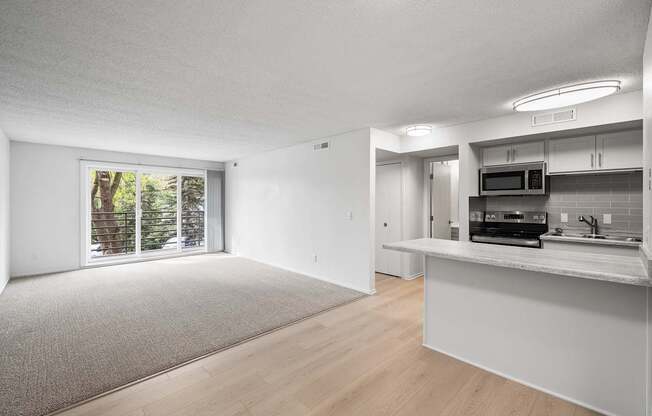 an empty living room and kitchen with a door to a patio