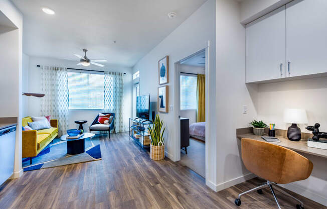 a living room with a couch and a desk and a window