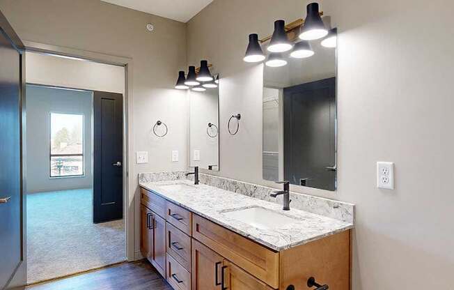 a bathroom with a double vanity sink, two mirrors, and a door to the walk-through closet