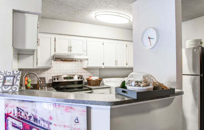 a kitchen with white cabinets and a counter top and a refrigerator