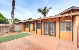 A building with a brown and tan exterior has a green lawn in front.