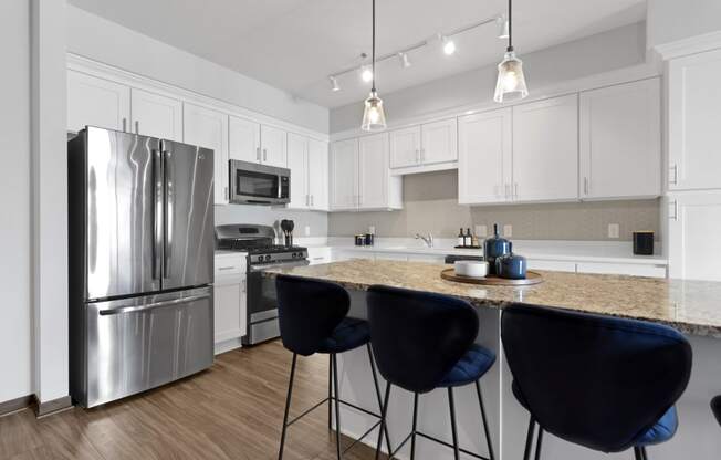a kitchen with stainless steel appliances and an island with blue chairs