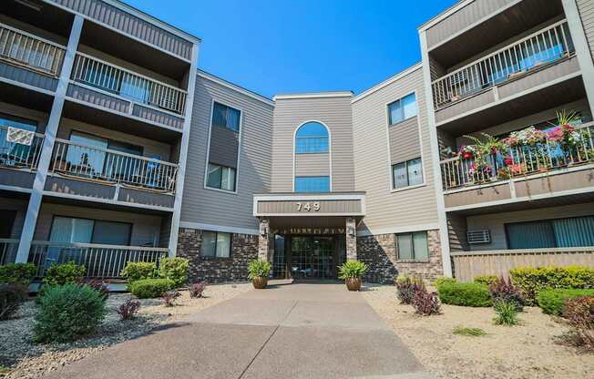 an exterior view of an apartment building with a sidewalk and potted plants