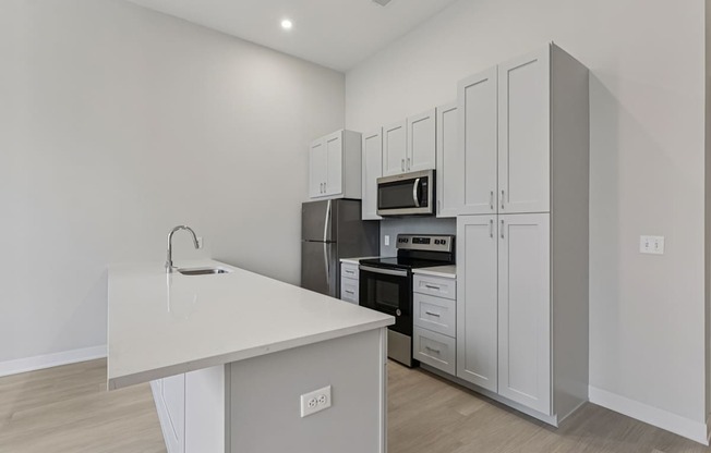 A kitchen with white cabinets and a white countertop.