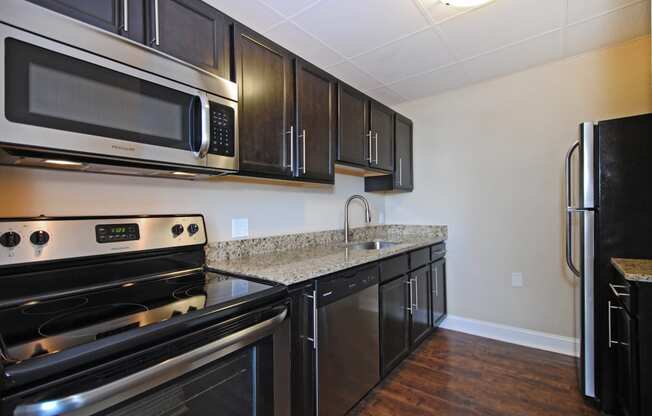 Kitchen with Stainless Steel Appliances, Dishwasher, cabinet space, and hardwood floors at Bancroft Apartments in Saginaw, MI