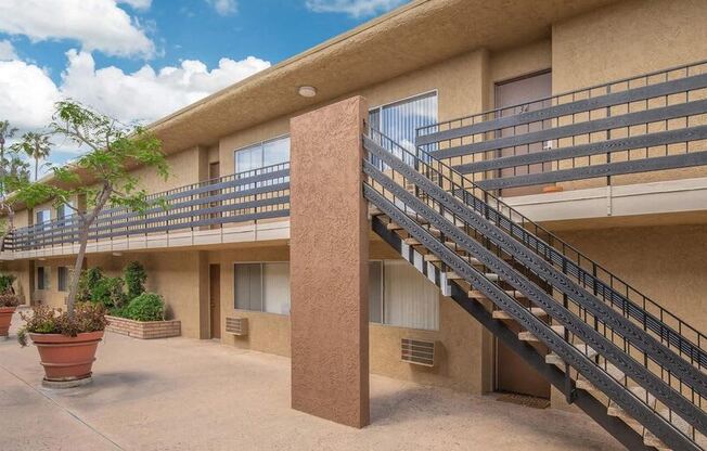 a building with a staircase and a balcony with potted plants at Villa La Paz Apartments, Bellflower, 90706