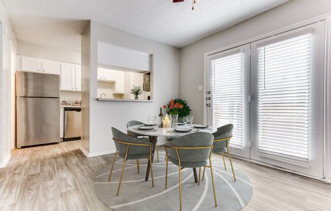 a dining room with a table and chairs and a kitchen with stainless steel appliances