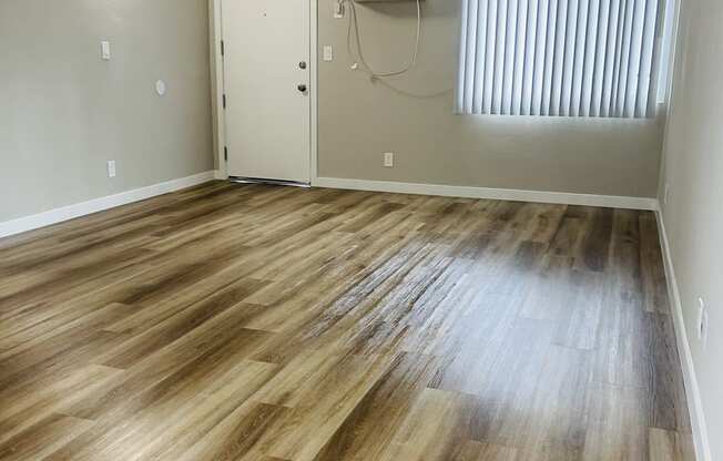 an empty living room with wood flooring and a window