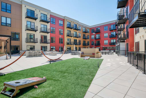 a courtyard with a hammock and a picnic table in front of an apartment building
