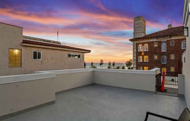 the view of the sunset from the balcony of a house with a roof