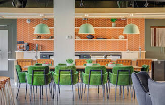 a large table with green chairs and a kitchen in the background