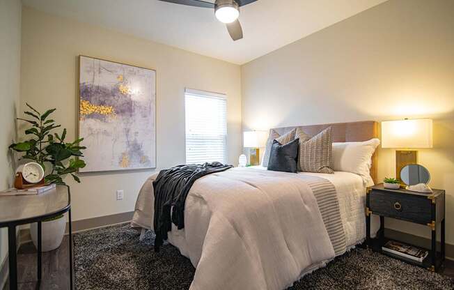 A bedroom with a bed, nightstand, and a ceiling fan.