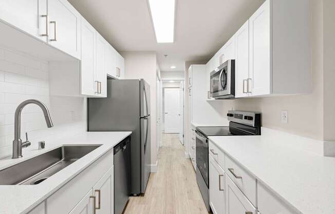 A modern kitchen with white cabinets and black appliances.