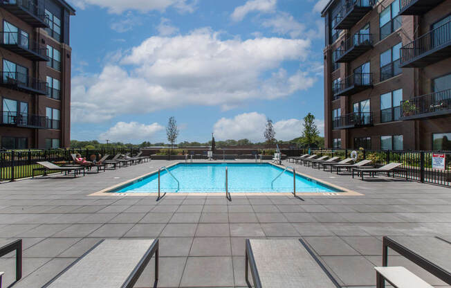 Maple Street Lofts - Big Pool with Deck, and Lounge Chairs, Surrounded by Apartment Building.