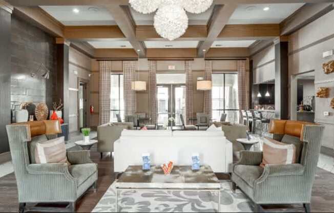 A spacious living room with grey chairs and a patterned rug.
