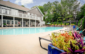 A pool area with a building and a planter.