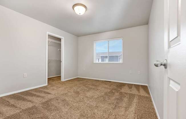 A room with a carpeted floor and a window with blinds.