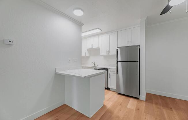A kitchen with a refrigerator, sink, and cabinets.