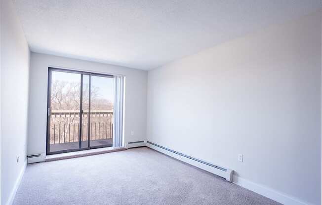 an empty bedroom with a sliding glass door and a balcony