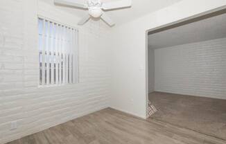 A room with a white ceiling fan and a window with blinds.