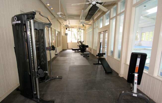 a gym with weights and cardio equipment in a building with windows