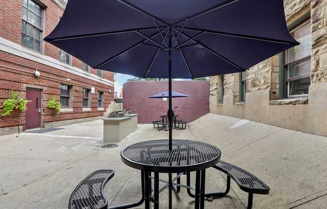 A purple umbrella is open over a table with two chairs.