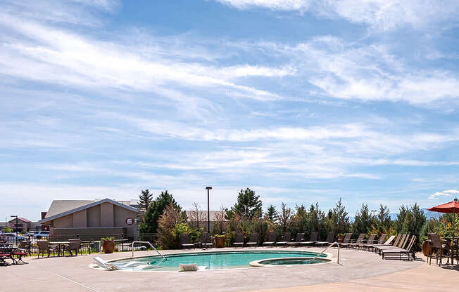 A large outdoor swimming pool surrounded by lounge chairs and umbrellas.