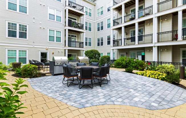 a patio with a grill and a table and chairs in front of an apartment building at Metro 303, Hempstead, NY 11550