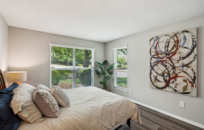 A bedroom with a large bed and a painting on the wall.