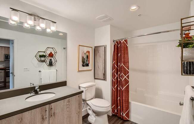 A bathroom with a toilet, sink, and a red shower curtain.