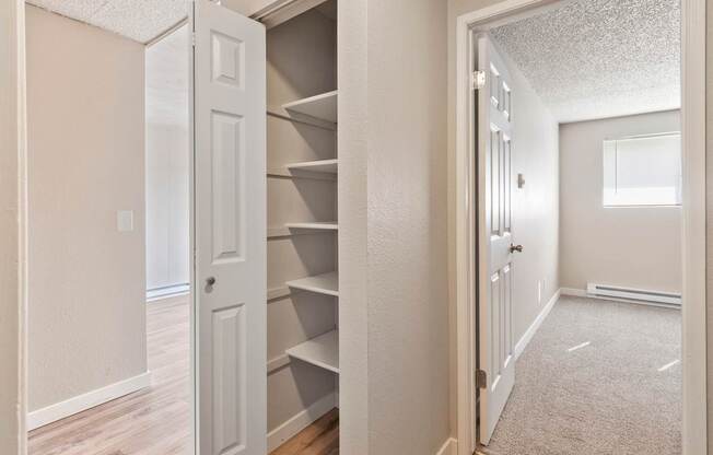 A white door is open to a hallway with a carpeted floor.