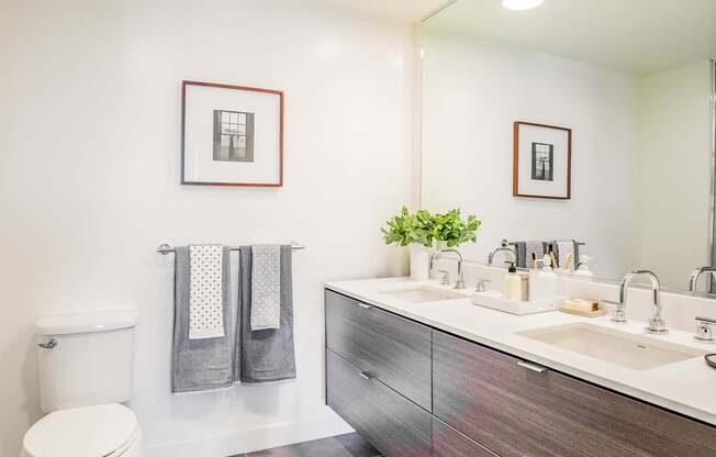 A bathroom with a toilet, sink, and mirror.