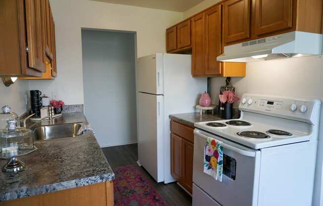 Kitchen with granite countertop, oven, refrigerator, sink, and wood cabinets, at Gale Gardens Apartments,