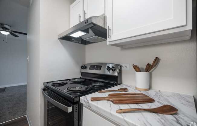 a kitchen with a stove top oven next to a counter top with wooden utensils