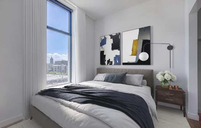 Bedroom with city view, queen sized bed, and decor