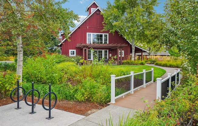 A red barn with a white fence and a walkway in front.