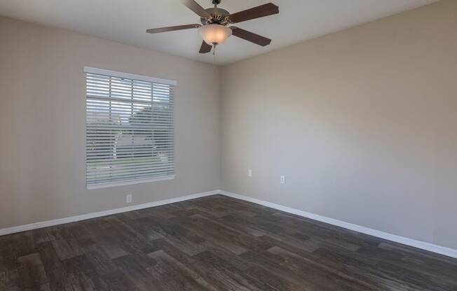 an empty living room with a ceiling fan and a window