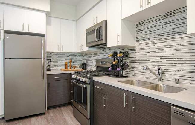 A modern kitchen with a stainless steel refrigerator and a stone backsplash.