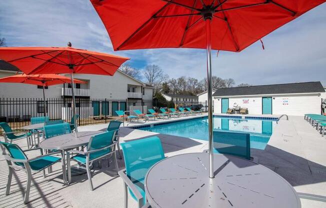 a pool with chairs and umbrellas around it at Cleo Apartments, Athens, Alabama