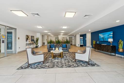 A spacious lobby with a blue accent wall and a large screen TV at The Waterford At Rocketts Landing Apartments, PRG Real Estate, Richmond, Virginia