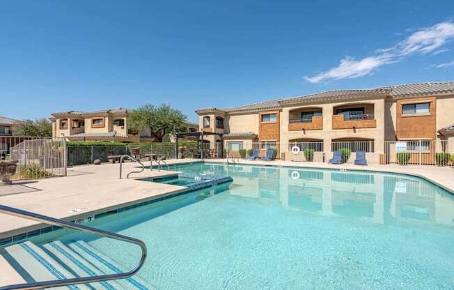 A swimming pool in front of a building with a clear blue sky.